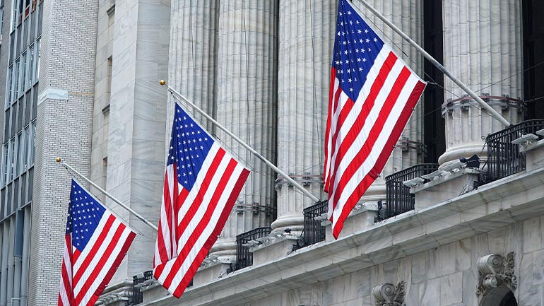 U.S. flags displayed on the exterior of a large office building.