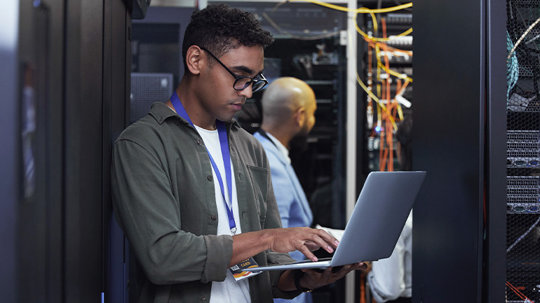 IT professionals working with laptops in a data center.