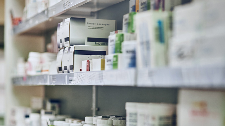 Close up of shelves stocked with various boxed and bottled medications.