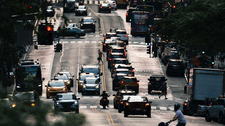 Vehicles travelling on a multi-lane highway at sunset, with dense traffic and warm light.
