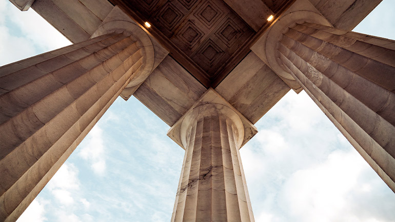 Stone columns viewed from below, supporting a classical-style structure.