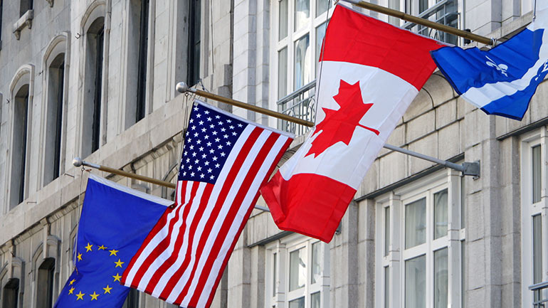 European Union, American and Canadian flags flying outside of an office building 