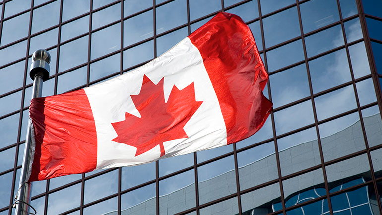 A Canadian flag waving in front of an office building