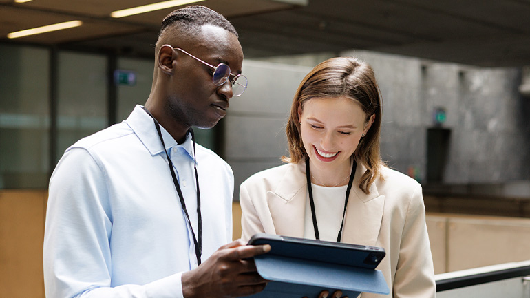 Two employees reviewing information on a tablet in an office lobby.