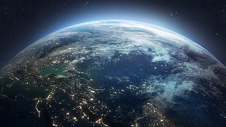 View of Earth from space showing illuminated land and clouds.