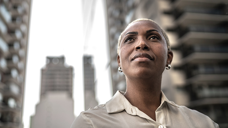 Close-up of a professional standing between tall corporate buildings.