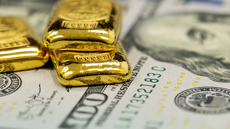 Gold bars positioned on top of U.S. currency.