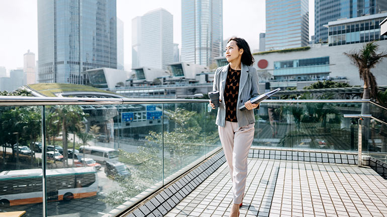 A woman surrounded by green landscape in the city.