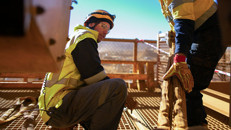 Mining workers handling equipment at a precious metals site.