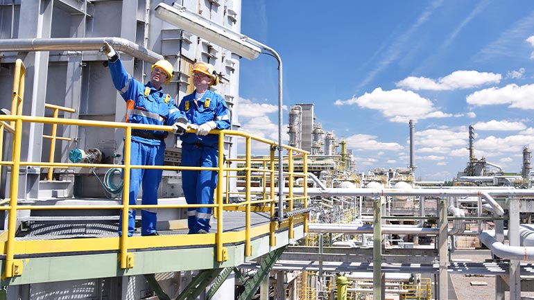 Two industrial workers outside an oil processing refinery