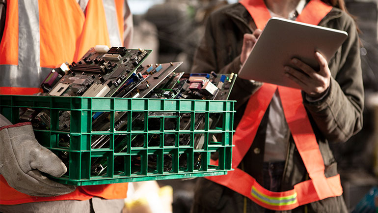 Des travailleurs tiennent des cartes mères et des déchets électroniques qui seront réutilisés.