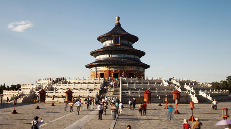 Temple of Heaven in Beijing with visitors on a wide stone terrace under clear sky.
