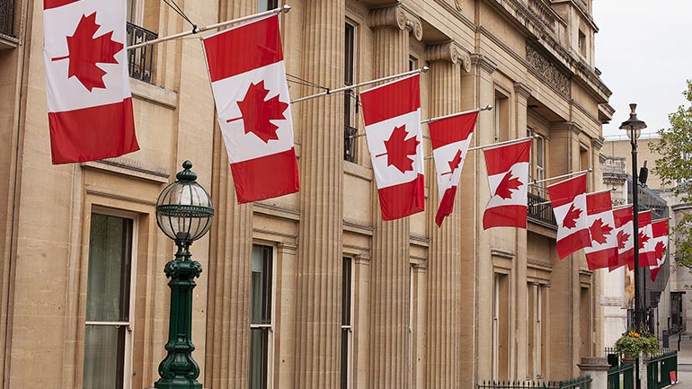 Rangée de drapeaux canadiens à l’extérieur d’un immeuble gouvernemental.