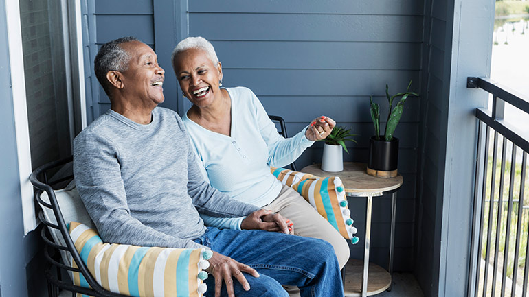 Two elderly individuals sitting on their porch.