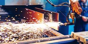 Industrial robot welding metal with sparks.