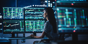 Person analyzing financial data on multiple computer screens.